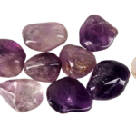 A pile of large amethyst tumbled stones with deep purple, to violet hues with a quarter for comparison. Most are larger than the quarter.