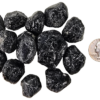 A pile of tumbled apache tears, showing deep black with some white patterns, and a quarter for comparison. Most are the same size or larger than the quarter.