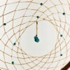 A closeup of a turquoise chunk and beads woven into a dream catcher.