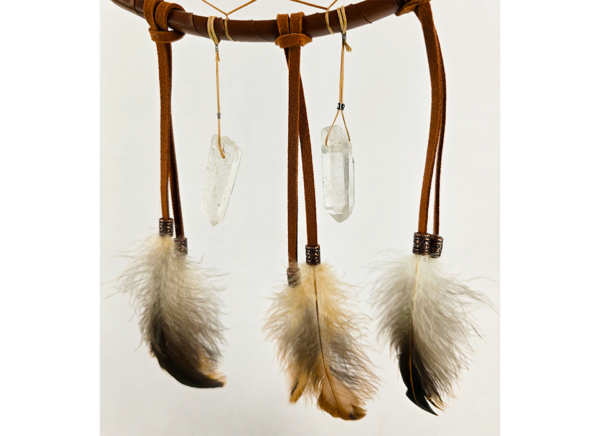 The bottom of a dream catcher that shows feathers held on by copper beads, with two quartz crystals hanging next to the feathers.