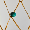 A closeup of a turquoise bead woven into a dream catcher.