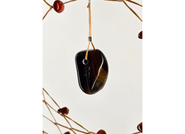 A closeup of a tiger's eye chunk hanging as the centerpiece of a dream catcher.