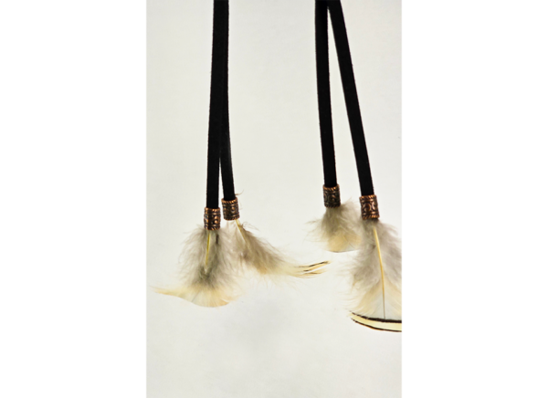 Feathers hanging from a dream catcher held on by copper beads.