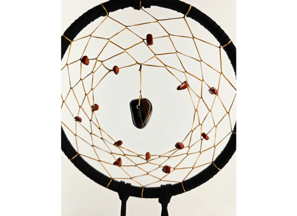 A black dream catcher with a chunk of tiger's eye as the centerpiece, with smaller stones woven around the center, and draped with feathers.