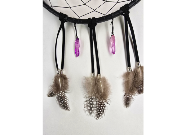 The bottom of a dream catcher showing it is draped with two purple quartz crystals, and feathers held on with silver beads.
