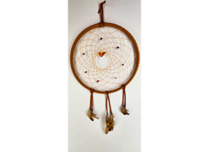 A light brown dream catcher with baltic amber as the centerpiece, surrounded by smaller brown stones woven in, draped with feathers.