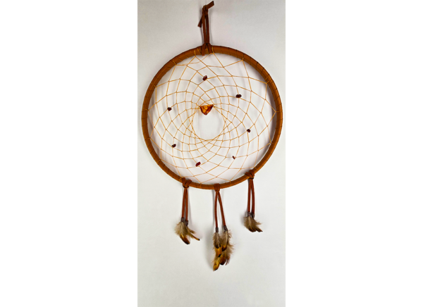 A light brown dream catcher with baltic amber as the centerpiece, surrounded by smaller brown stones woven in, draped with feathers.