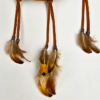 Feathers hanging from a dream catcher, attached with copper beads.