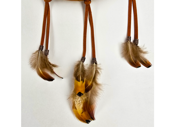 Feathers hanging from a dream catcher, attached with copper beads.