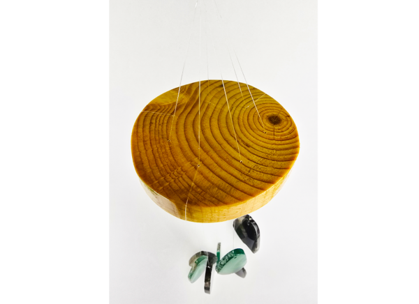 An agate windchime displaying the wood base that is polished and shows the rings in the wood, and a shiny finish.