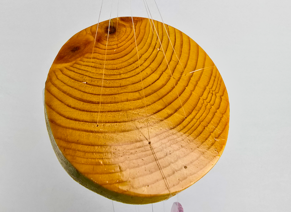 An agate windchime displaying the wood base that is polished and shows the rings in the wood, and a shiny finish.