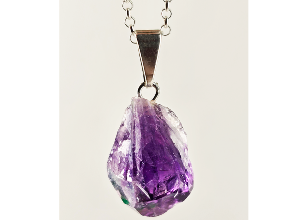 A closeup of an amethyst pendant with a silver plated bail. It's color is violet.