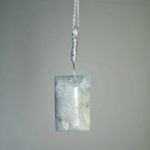 Aquamarine pendant with light blue, creamy yellowish white flowing through the polished stone, with a wire-wrapped silver bail.