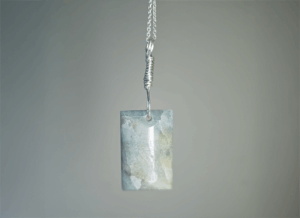 Aquamarine pendant with light blue, creamy yellowish white flowing through the polished stone, with a wire-wrapped silver bail.