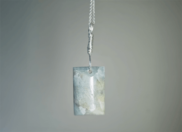 Aquamarine pendant with light blue, creamy yellowish white flowing through the polished stone, with a wire-wrapped silver bail.