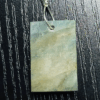 The back of aquamarine pendant with silver wire wrapped bail, showing more creamy yellowish white flowing through stone, and light blue.