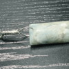 Aquamarine pendant sideways showing the shape of the cabochon, with light blue, creamy yellowish white flowing through the polished stone, with a wire-wrapped silver bail.