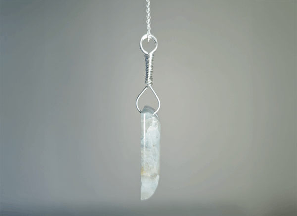 Side shot of aquamarine pendant with silver wire-wrapped bail.