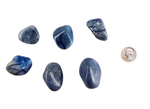 Large tumbled blue quartz stone in soft shades of sky blue with subtle marbling, shown next to a quarter for size comparison, the stones are larger than the quarter.