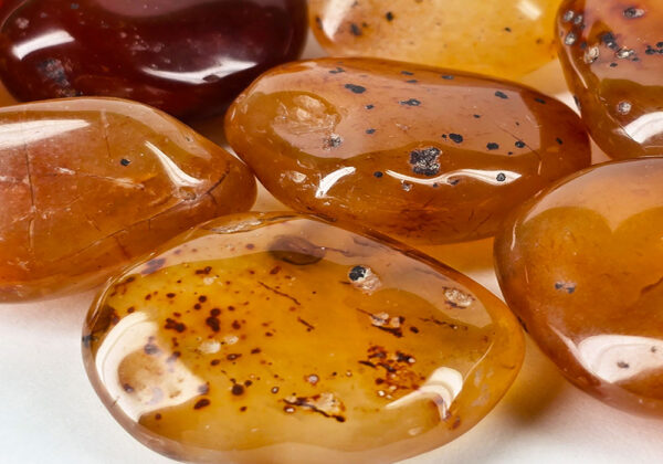 A closeup of tumbled carnelian medium, with a brown honey color with some tranclucency to the polished stones.