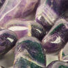 A closeup of small chevron amethyst polished stones, with deep purple to violet, with white in chevron patterns on the stones.