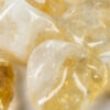 A closeup of small tumbled citrine, with a light hone color, with some milky white, and translucency to the stones.