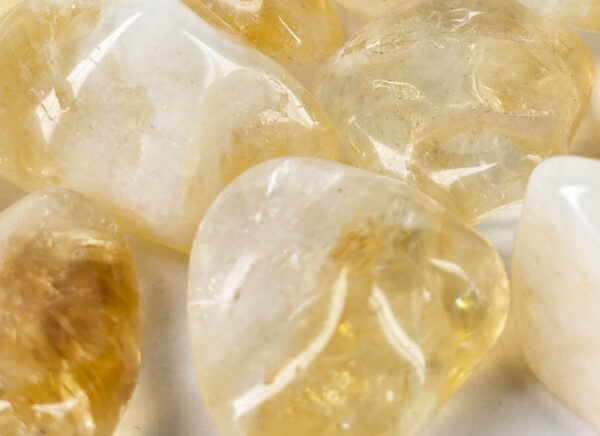 A closeup of small tumbled citrine, with a light hone color, with some milky white, and translucency to the stones.