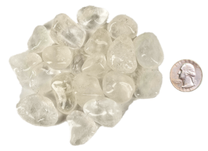 A pile of small quartz tumbled stones, that are mostly transparent with some inclusions, with a quarter for comparison. Most are slightly smaller than the quarter.