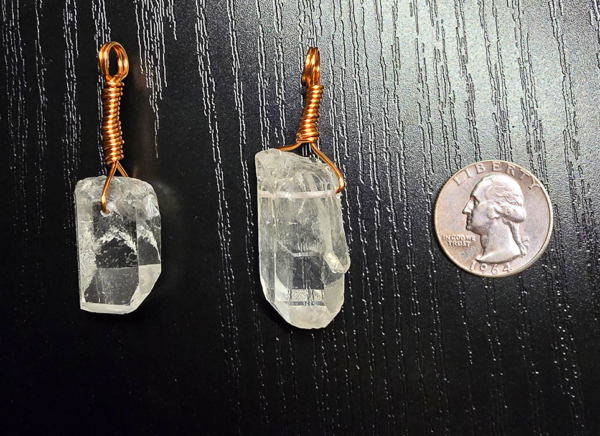 Two quartz pendants with copper wire wrapped bails with a quarter for size comparison. Each crystal is slightly larger than the quarter.