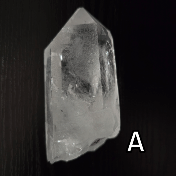 Large clear quartz crystal point with black backround, labeled 'A'.