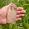 Large clear quartz crystal point with grass backround, labeled 'A'.