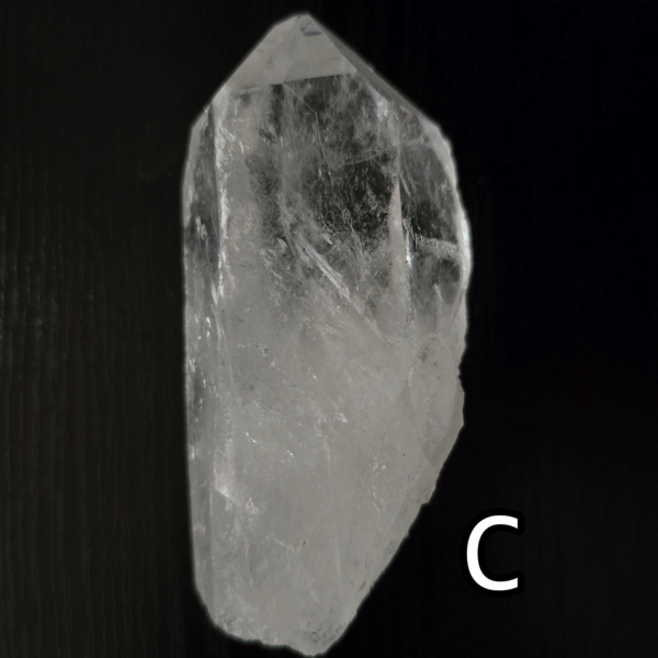 Large clear quartz crystal point with black backround, labeled 'C'.
