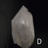 Large clear quartz crystal point with black backround, labeled 'D'.