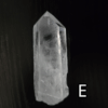 Large clear quartz crystal point with black backround, labeled 'E'.