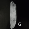 Large clear quartz crystal point with black backround, labeled 'G'.