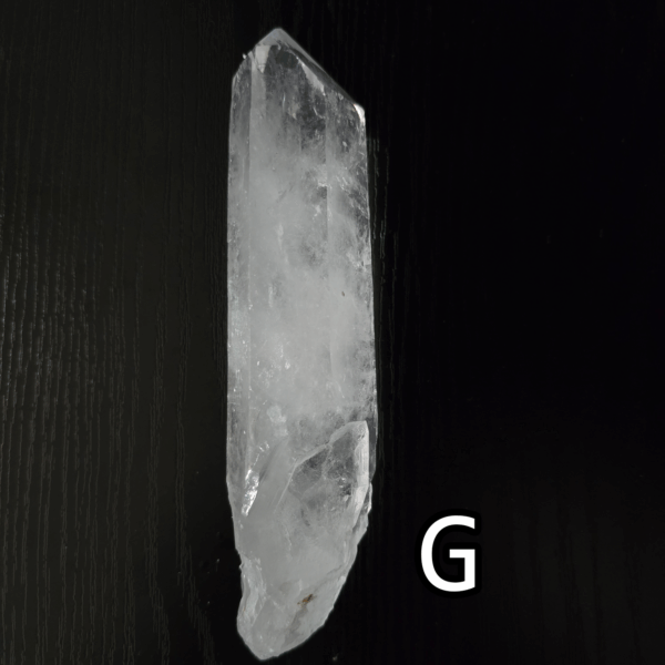 Large clear quartz crystal point with black backround, labeled 'G'.