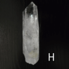 Large clear quartz crystal point with black backround, labeled 'H'.