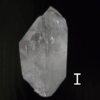 Large clear quartz crystal point with black backround, labeled 'I'.