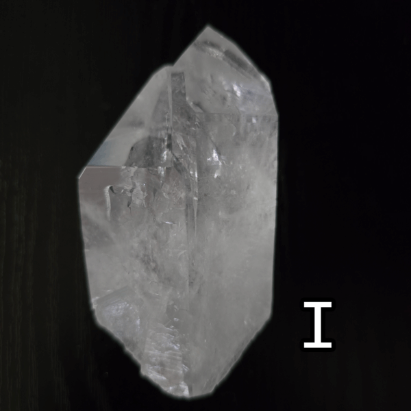 Large clear quartz crystal point with black backround, labeled 'I'.