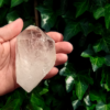 A large clear quartz point in the palm of a hand, it is quite large.