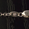 A closeup of the tag on the rolo adjustable sterling silver necklace, it is stamped '925 ITALY'.