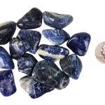 A pile of medium sodalite tumbled stones, showing deep blues and a range of milky to creamy white patterns with a quarter for comparison. Most are the size of the quarter and slightly larger.
