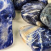 Closeup of medium sodalite tumbled group, showing deep blues and a range of milky to creamy white patterns.