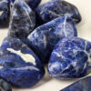 Closeup of small sodalite tumbled group, showing deep blues and a range of milky to creamy white patterns.