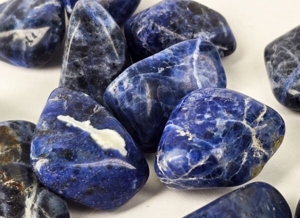 Closeup of small sodalite tumbled group, showing deep blues and a range of milky to creamy white patterns.