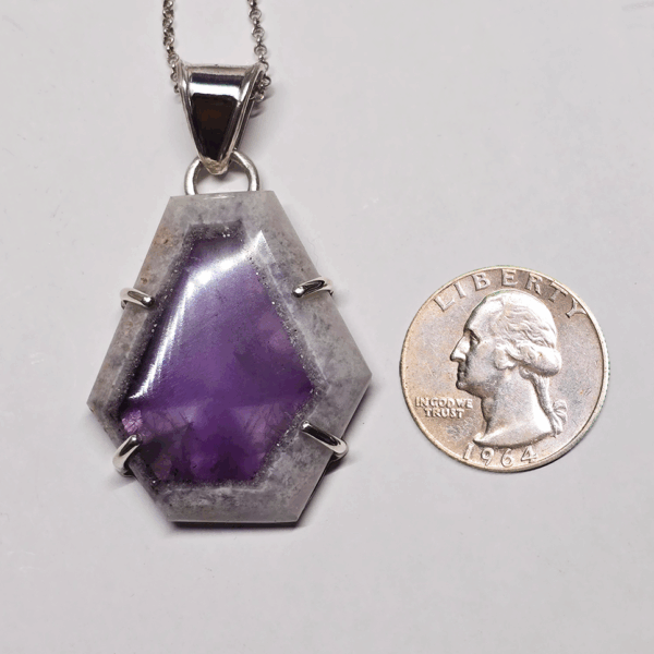 Atomic amethyst pendant with sterling silver posts securing stone, and a bail. There is a quarter for size comparison.